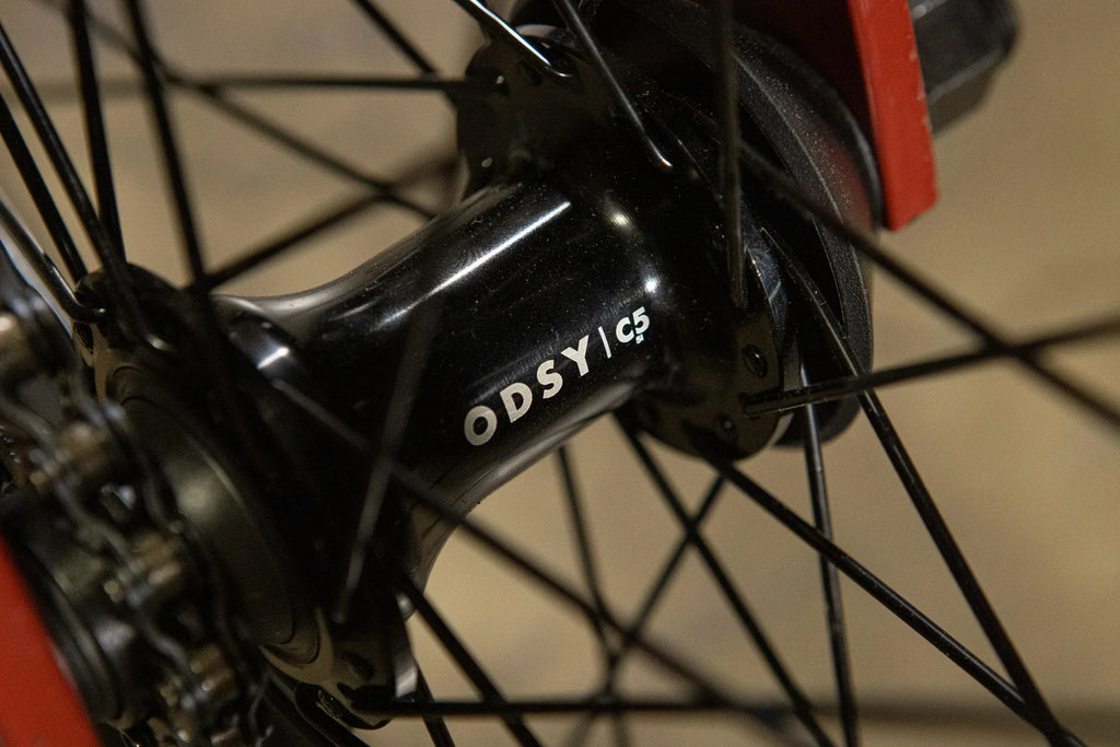 Gros plan d'un moyeu arrière de vélo BMX noir marqué Odsy C5 avec rayons.