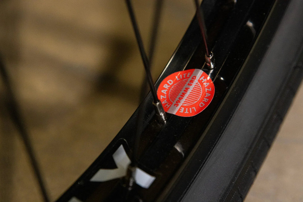 Gros plan d'une jante de vélo noire avec un autocollant rouge Hazard Lite.