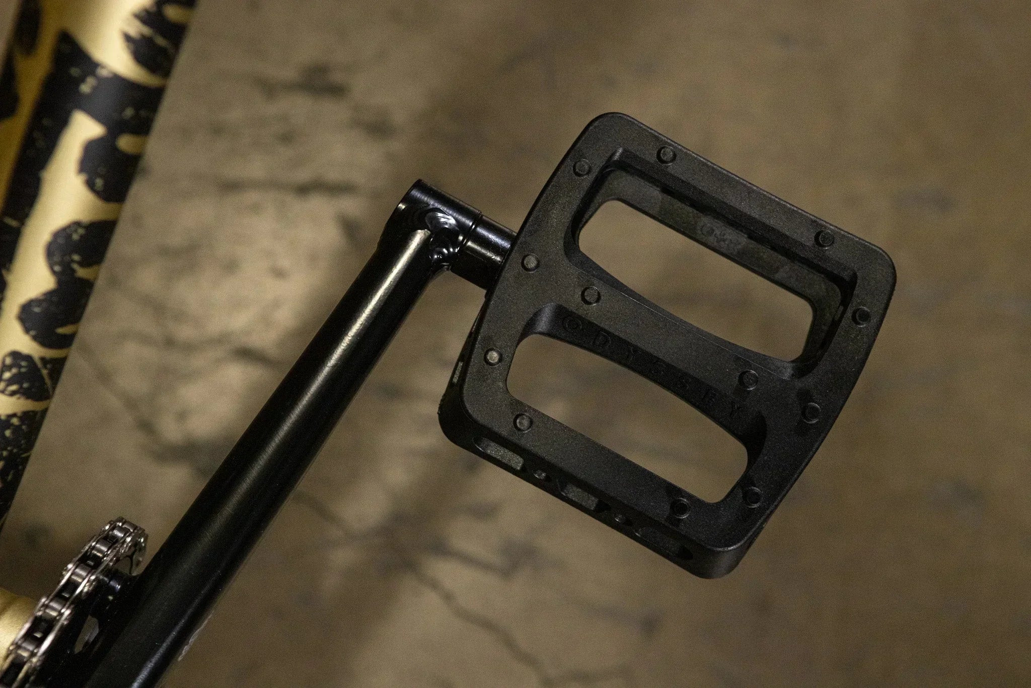 Gros plan d'une pédale de vélo BMX noire fixée à une manivelle.