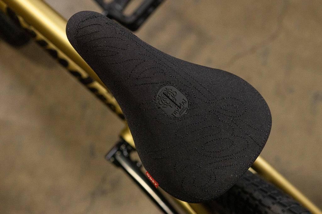 Selle de BMX noire avec logo embossé sur un cadre doré