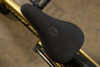 Selle de BMX noire avec logo embossé sur un cadre doré