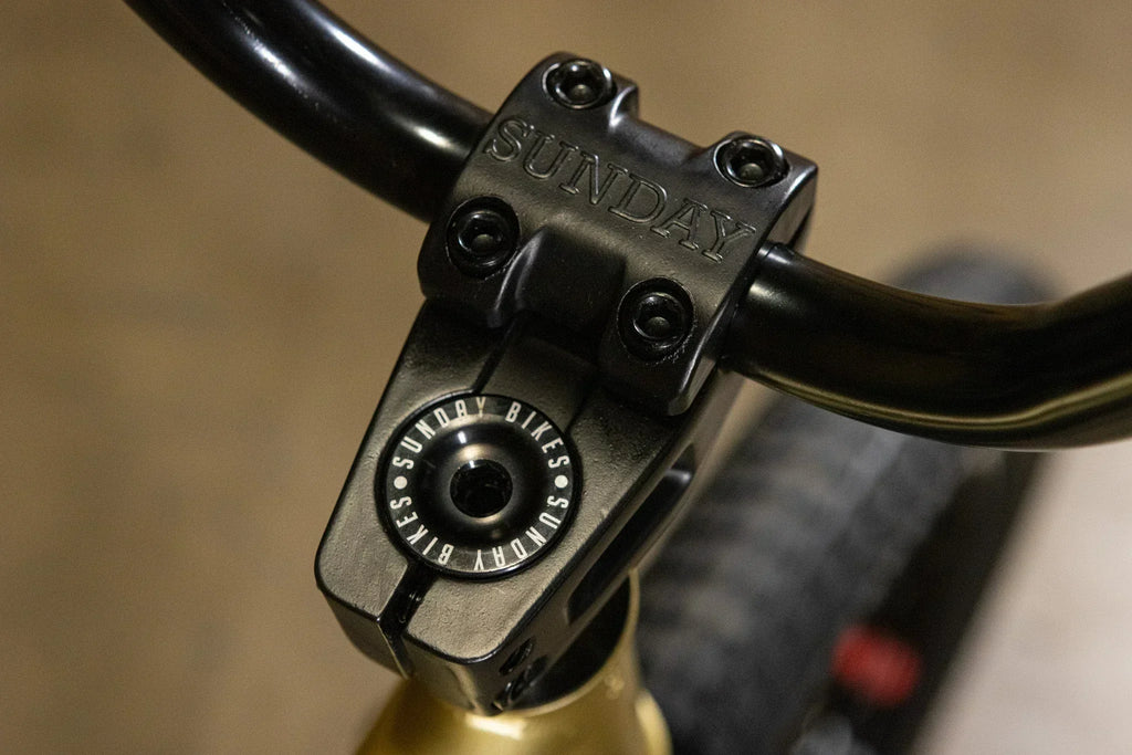 Gros plan d'une potence Sunday noire fixée sur un guidon de vélo BMX