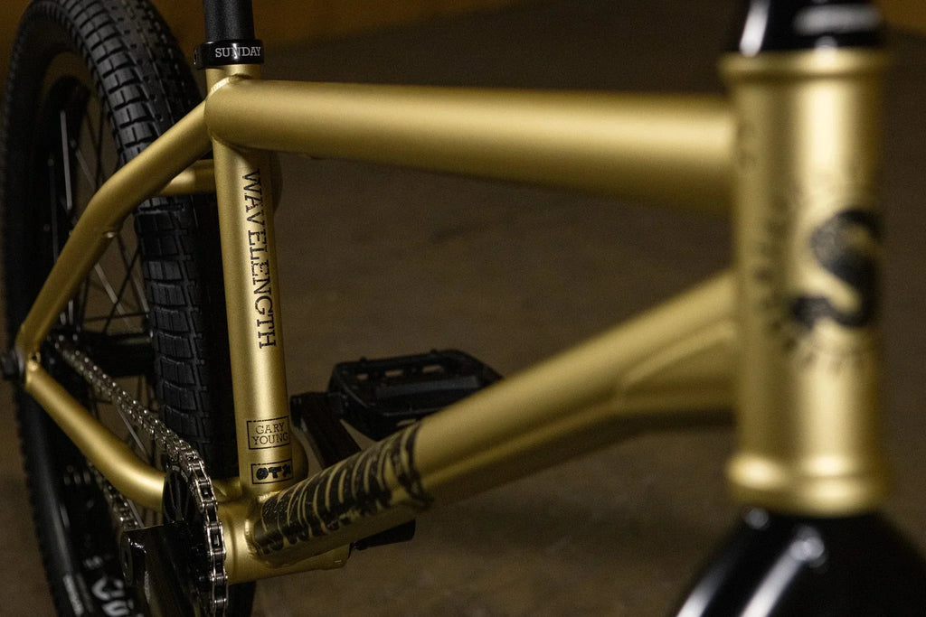 Gros plan du cadre doré d'un vélo BMX Sunday Wavelength