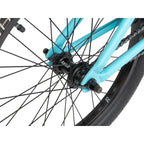 Détail de roue BMX bleu ciel avec moyeu Ratio, chaîne et pneu noir