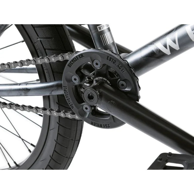 Détail de pédalier BMX noir avec chaîne et plateau gravé, cadre robuste pour vélo de freestyle