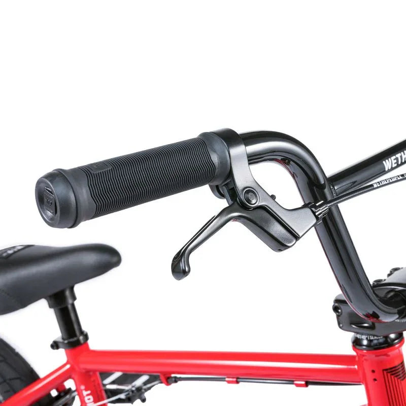 Poignées et levier de frein BMX noir sur cadre rouge, détail de vélo freestyle