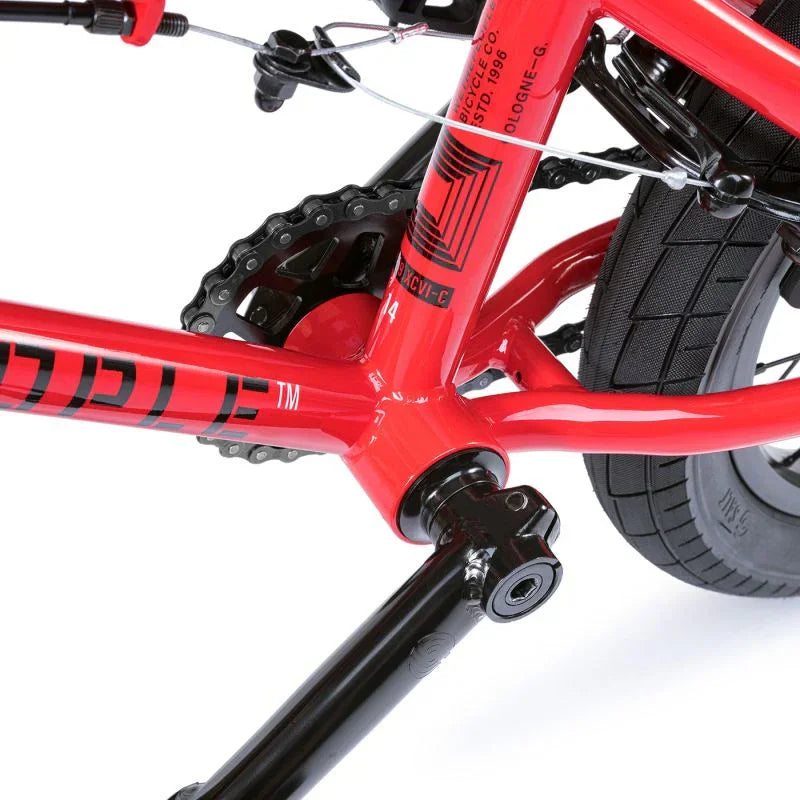 Vélo BMX rouge avec cadre robuste, chaîne et pédales noires, idéal pour tricks et freestyle
