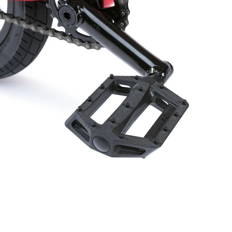 Pédale BMX noire avec crampons antidérapants, chaîne et cadre en vue rapprochée