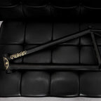 Matte black BMX bike frame with gold accents on a black padded surface
