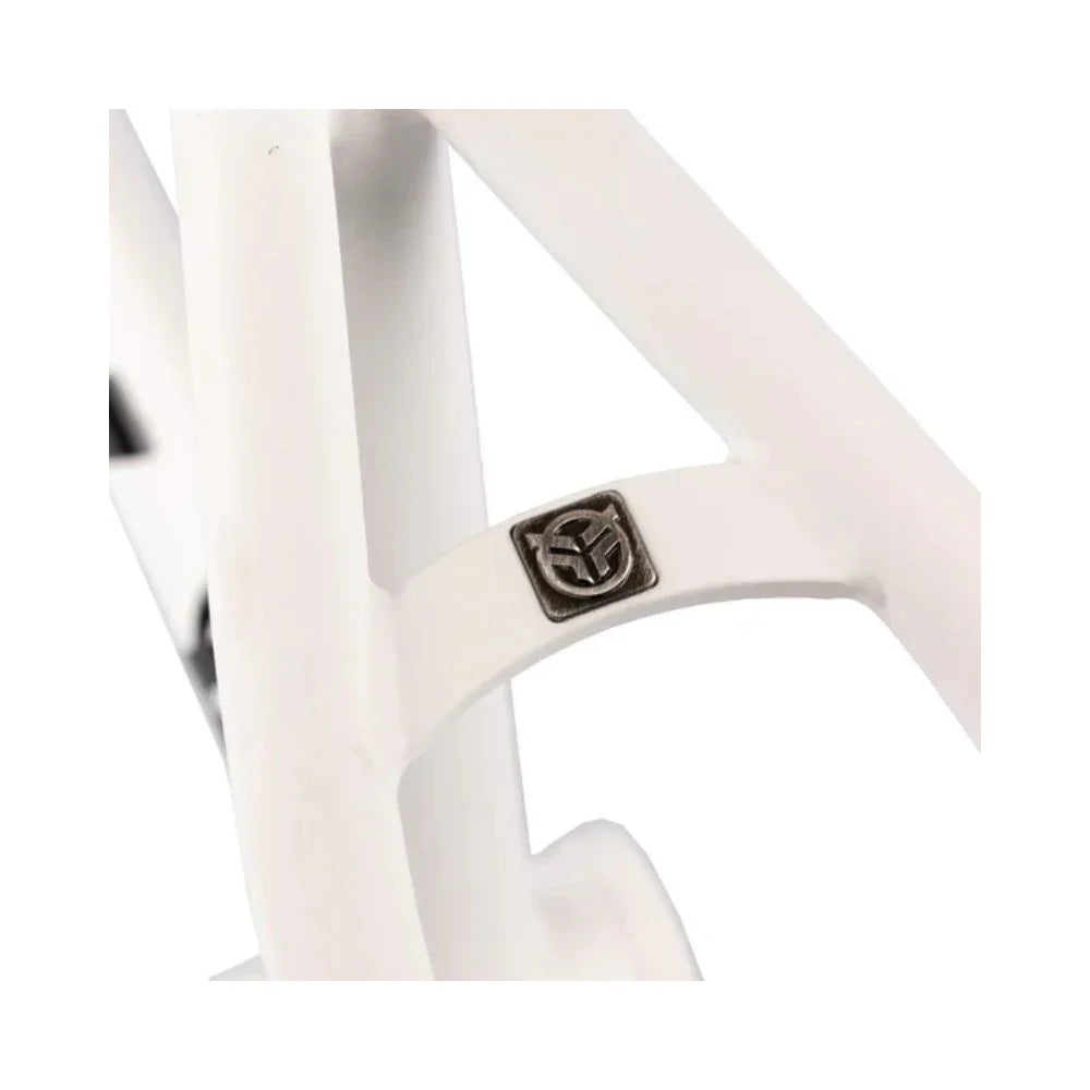 Matte white BMX frame close-up showing metal badge detail on rear triangle.