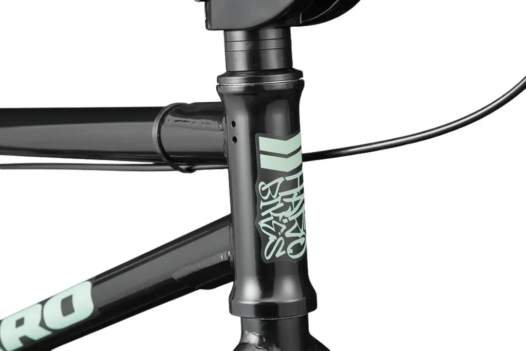 Détail du cadre noir d'un vélo BMX avec logos vert menthe