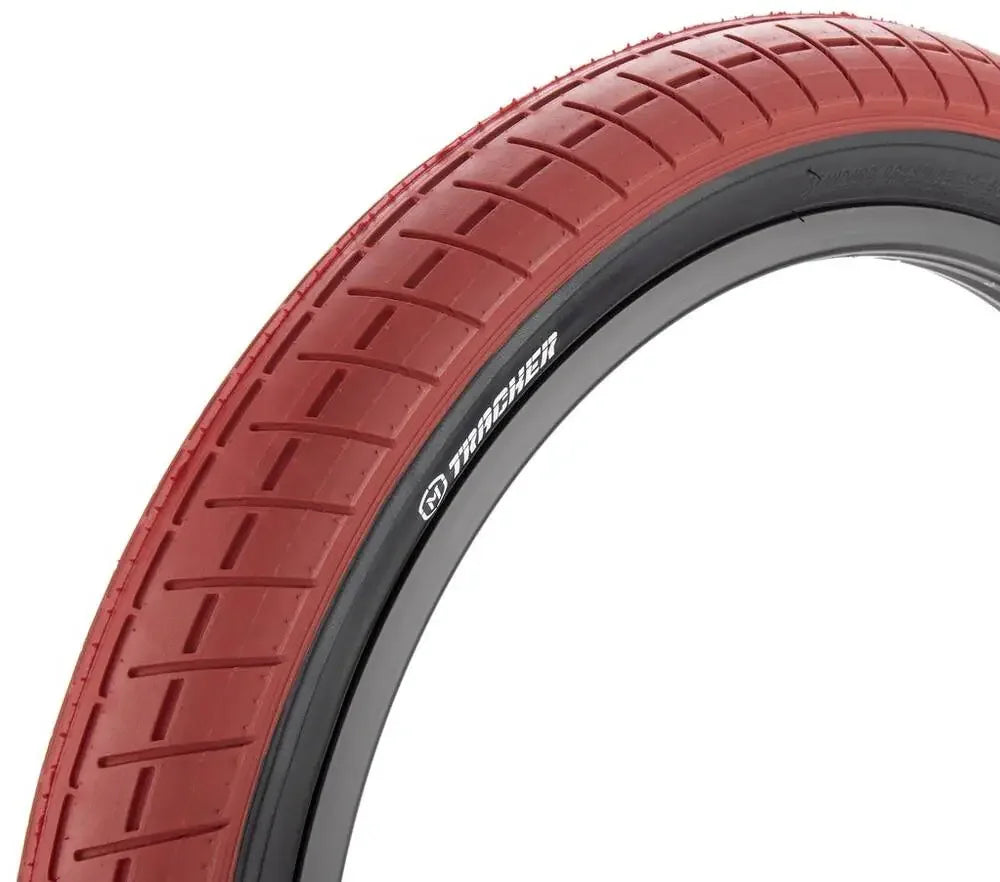 Red BMX bike tire with grooved tread pattern on a black rim, close-up view.