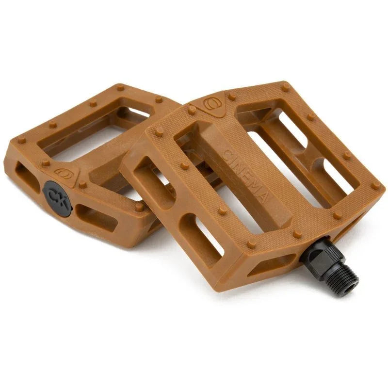 Pédales BMX marron avec grip texturé et logo Cinema, idéales pour le freestyle