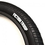 Close-up of black BMX tire with 'Fiction Troop' logo and textured tread pattern.