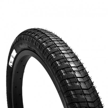 Black BMX bike tire with textured tread pattern, viewed from an angle on a white background.