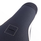 Détail de la languette d'une chaussure Vans noire avec logo embossé, coutures blanches et semelle blanche