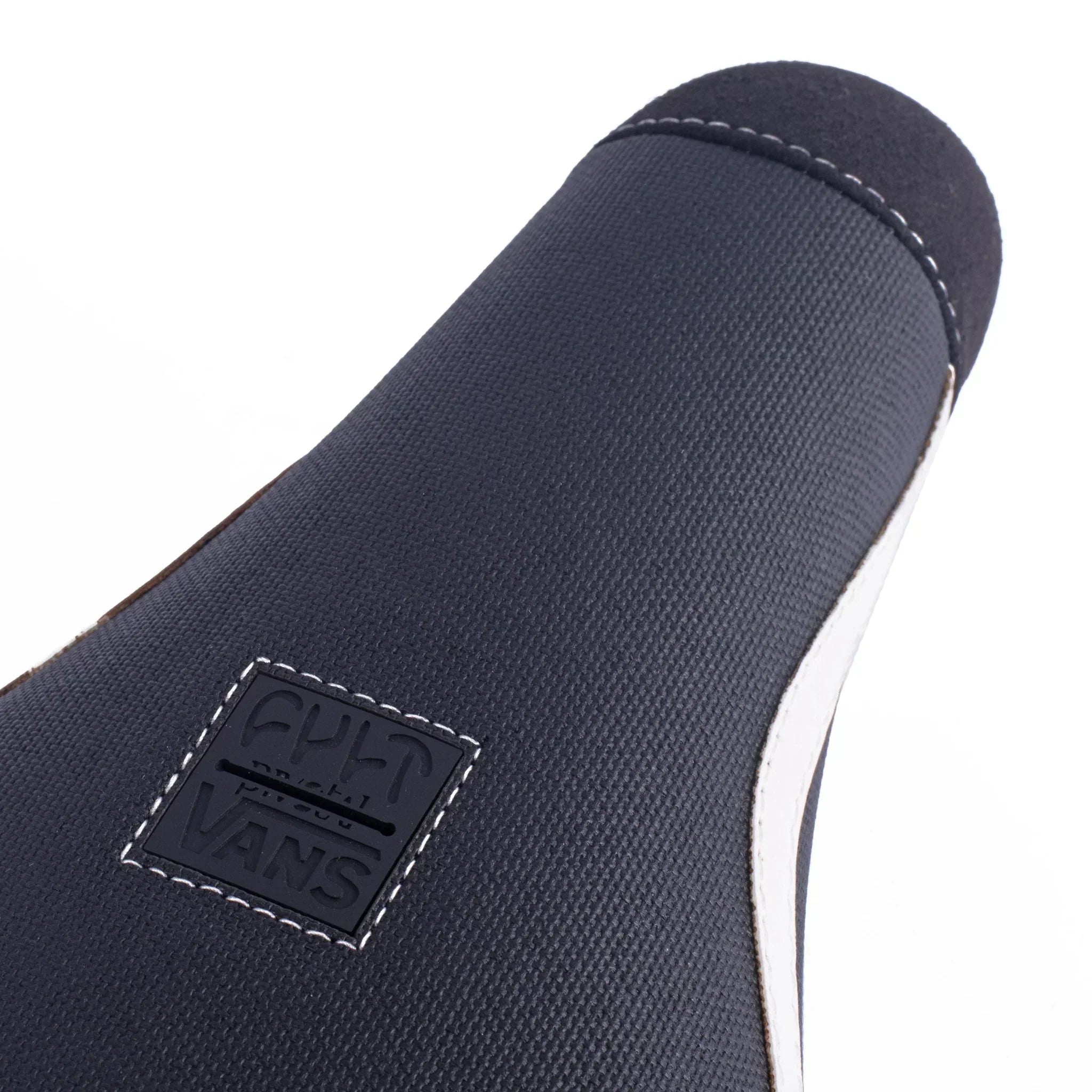 Détail de la languette d'une chaussure Vans noire avec logo embossé, coutures blanches et semelle blanche