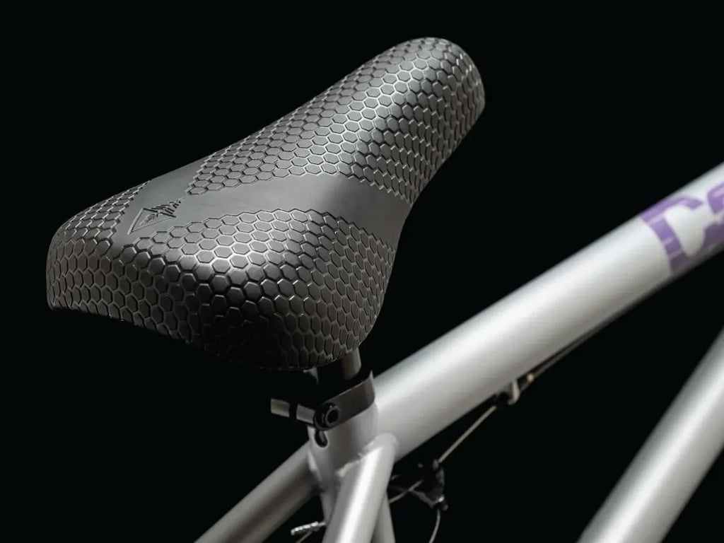 Selle BMX texturée hexagonale sur cadre argenté, design ergonomique pour vélo freestyle