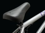 Selle BMX texturée hexagonale sur cadre argenté, design ergonomique pour vélo freestyle