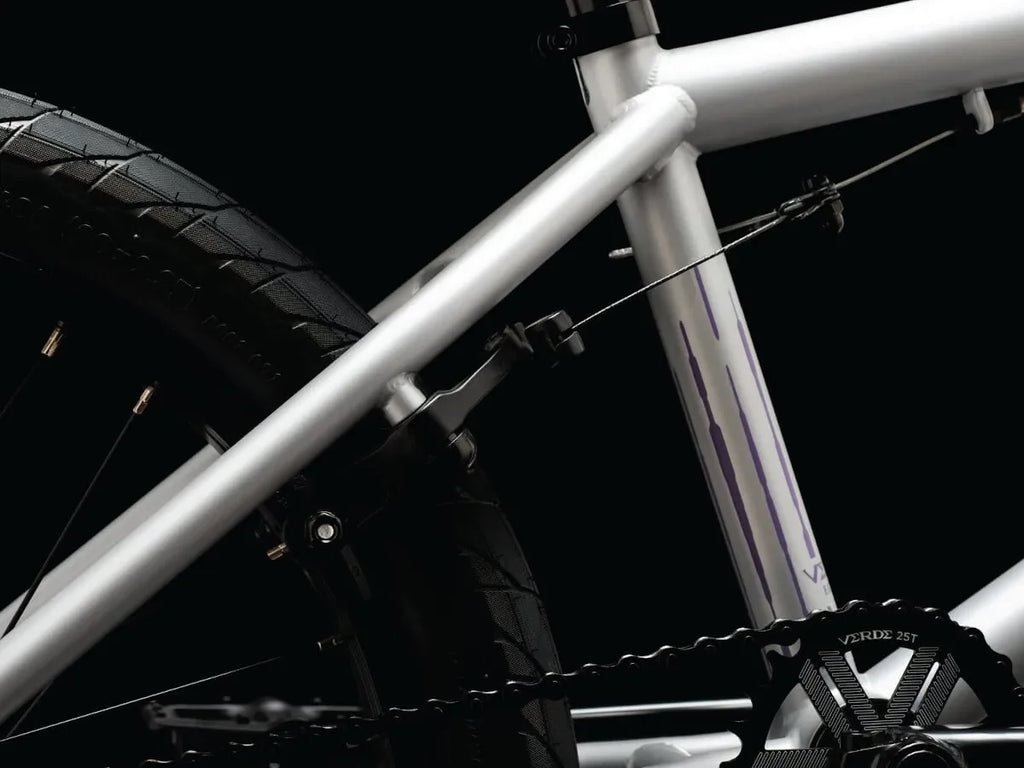 Cadre de BMX blanc avec détails violets et chaîne noire sur fond noir