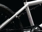 Cadre de BMX blanc avec détails violets et chaîne noire sur fond noir