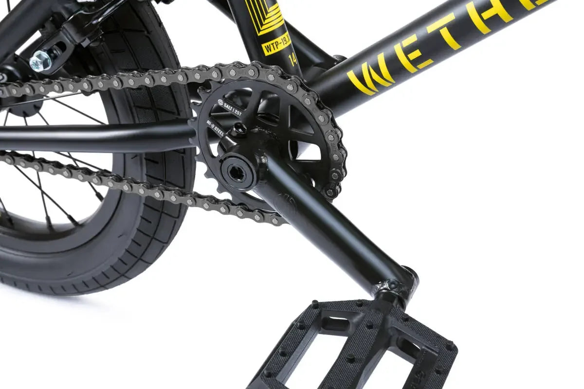 Détail de cadre BMX noir avec chaîne, pédalier et pneu, graphisme jaune vif pour freestyle