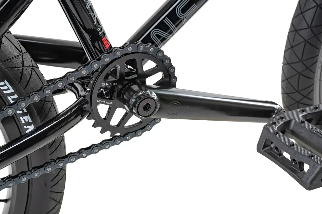 Détail pédalier BMX noir avec chaîne, plateau SALT 25T et pédales, cadre en alliage 6061-T6
