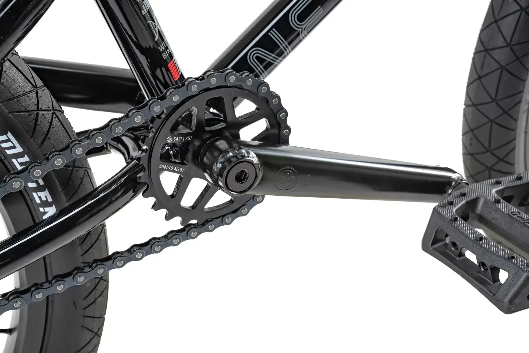 Détail pédalier BMX noir avec chaîne, plateau SALT 25T et pédales, cadre en alliage 6061-T6