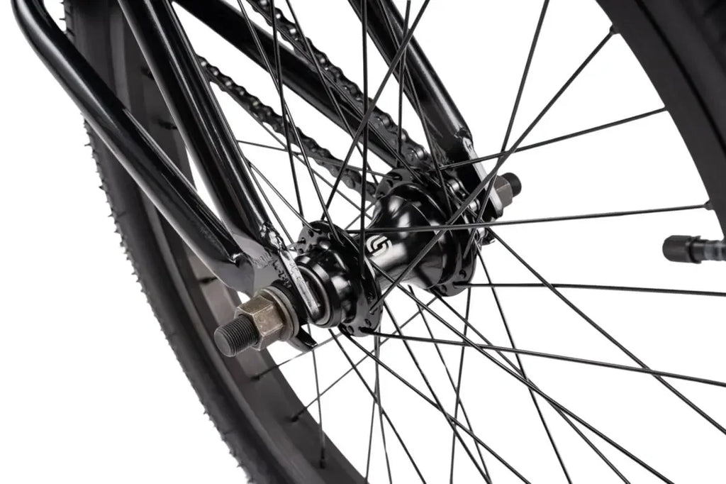 Détail roue BMX noire avec moyeu et chaîne, cadre robuste pour freestyle
