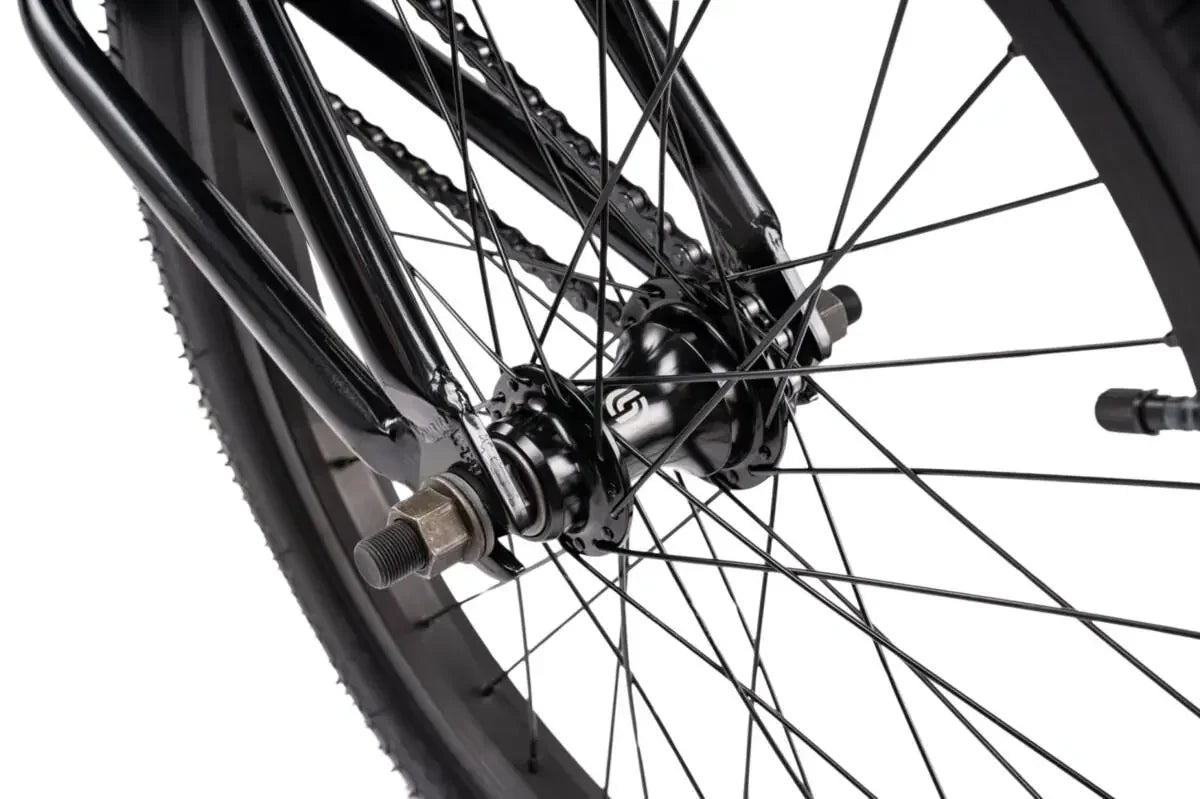 Détail roue BMX noire avec moyeu et chaîne, cadre robuste pour freestyle